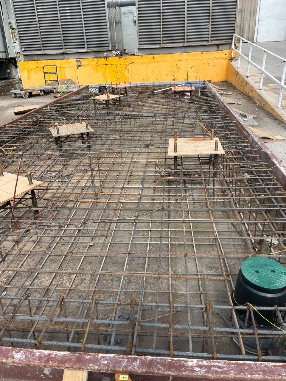 Formwork and two mats of tied rebar in place before the pour, with plywood templates holding the silo anchor bolts in position